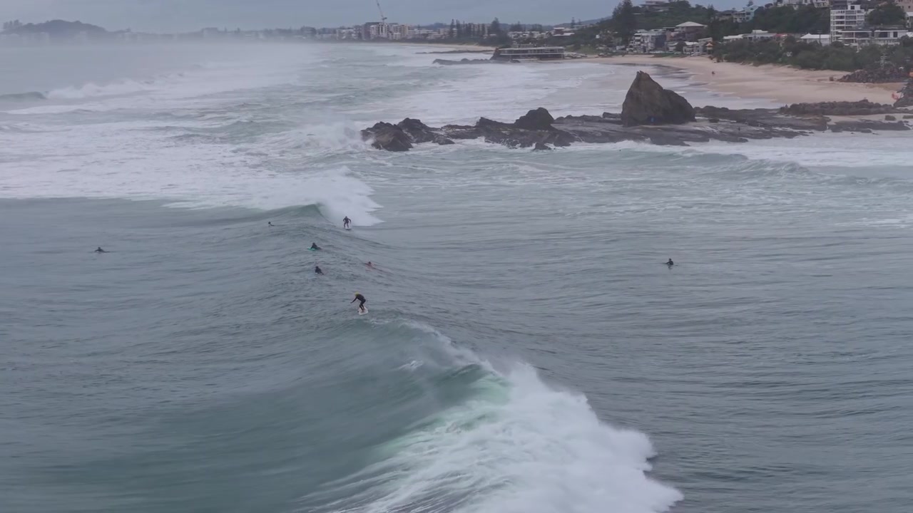 Surfare som fångar havsvågor nära klippformationerna längs Currumbin Beach – Flygfoto