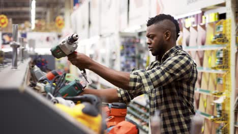 Male-buyer-selecting-drill-in-building-and-repair-shot-indoors