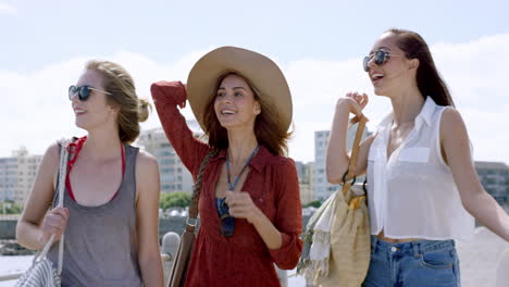 three young women tourists on summer vacation girl friends walking on beach promenade