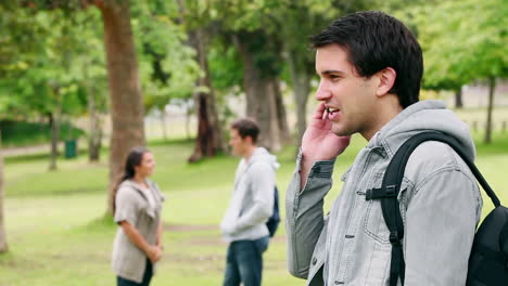 Man-talking-and-laughing-on-his-mobile-phone-as-he-stands-in-a-park