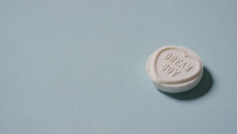 Hand-Picking-Up-Heart-Candy-With-Romantic-Message-Dream-Boy-On-Blue-Background