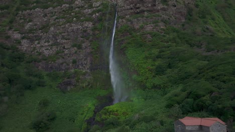 Volando-Hacia-Atrás-En-Una-Cascada-Con-Una-Casa-Local-En-Flores-Azores---Disparo-De-Un-Dron