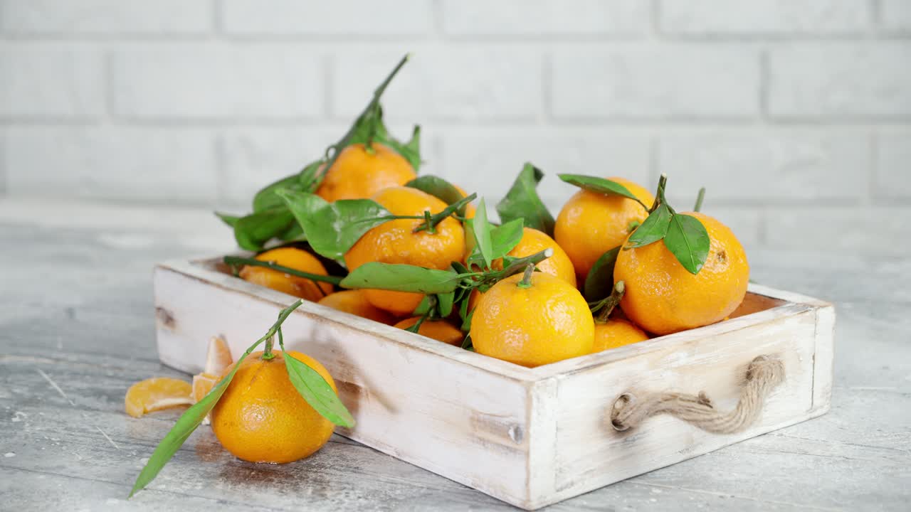 las mandarinas maduras con hojas en bandeja de madera giran lentamente.