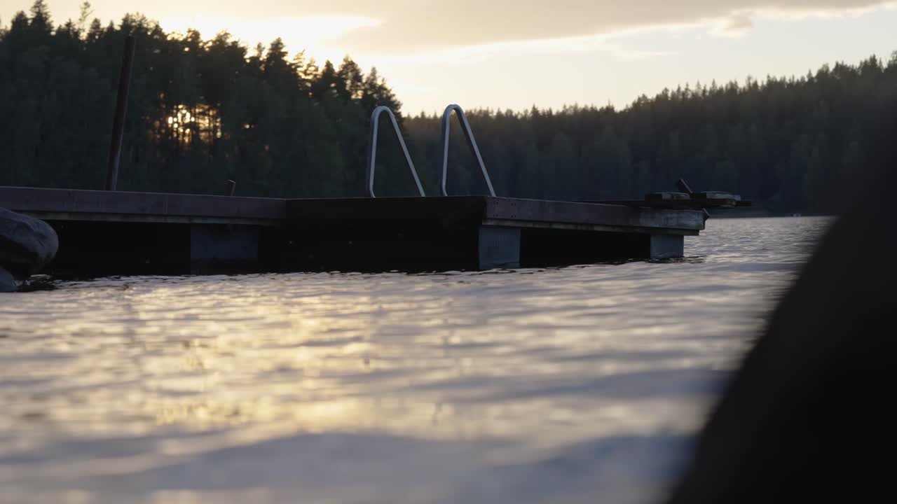 Flydende badeplatform på en krusende sø ved solnedgang. Optagelse fra lav højde.