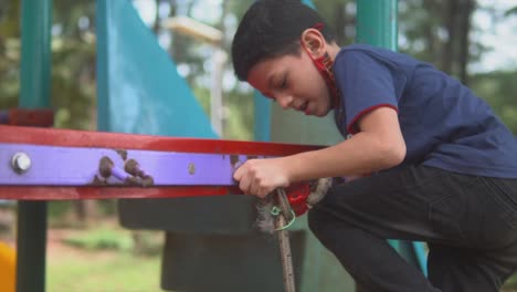 little boy playing on a colorful playground and people in the background