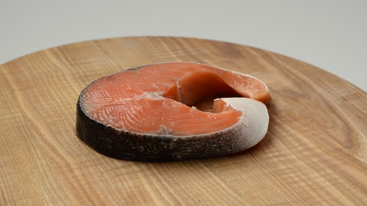 Trancio di salmone. Trancio di salmone salato su un tagliere di legno.