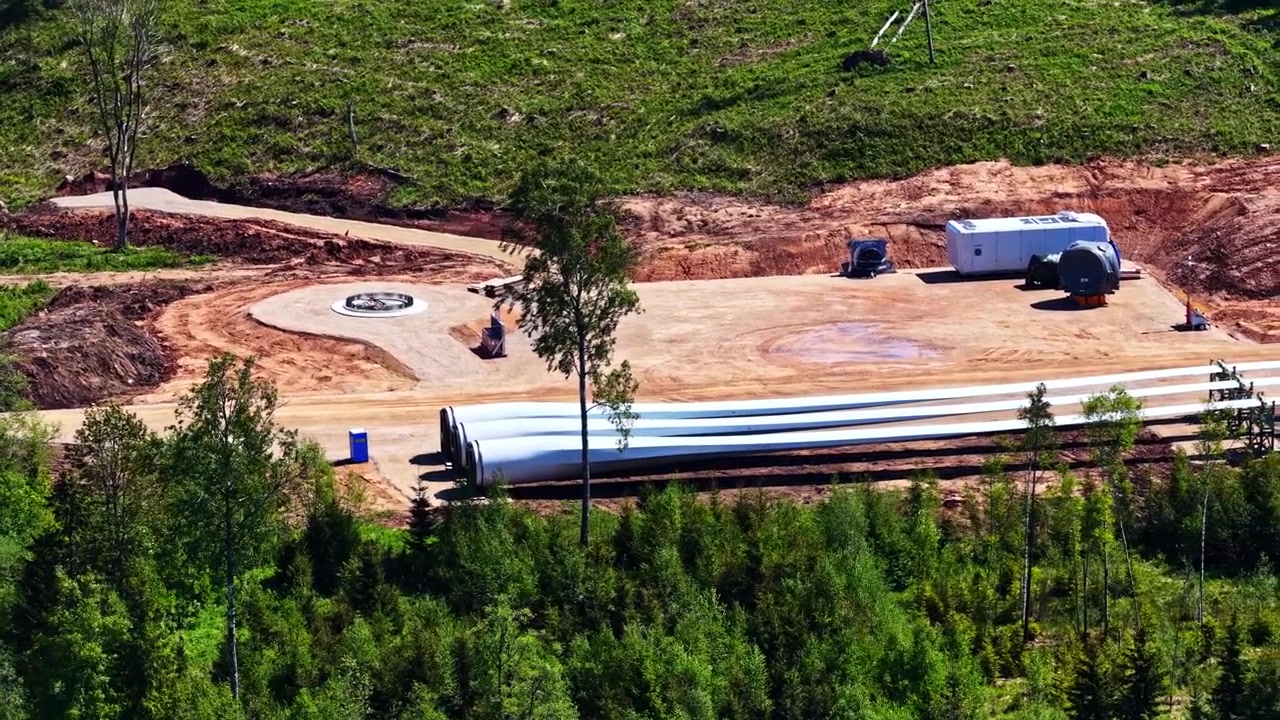 Aerial view of a wind turbine construction site showing blades and foundation ready for assembly