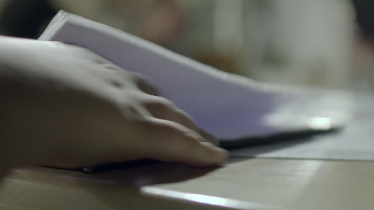 fotografía de cerca de la mano y los dedos de una persona desplazándose por el menú en un restaurante por la noche mientras está de vacaciones