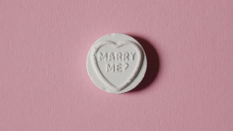 heart candy with marry me message on pink background