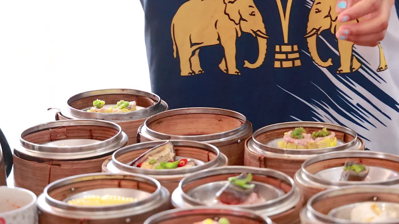 한 사람이 활기찬 재료로 전통적인 태국 요리 예술을 선보이며, 활기찬 환경에서 섬 바구니를 배열합니다.