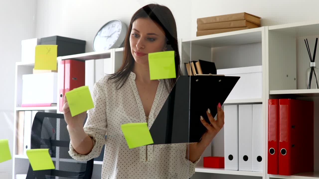 mujer de negocios marcando notas adhesivas en la pared de vidrio