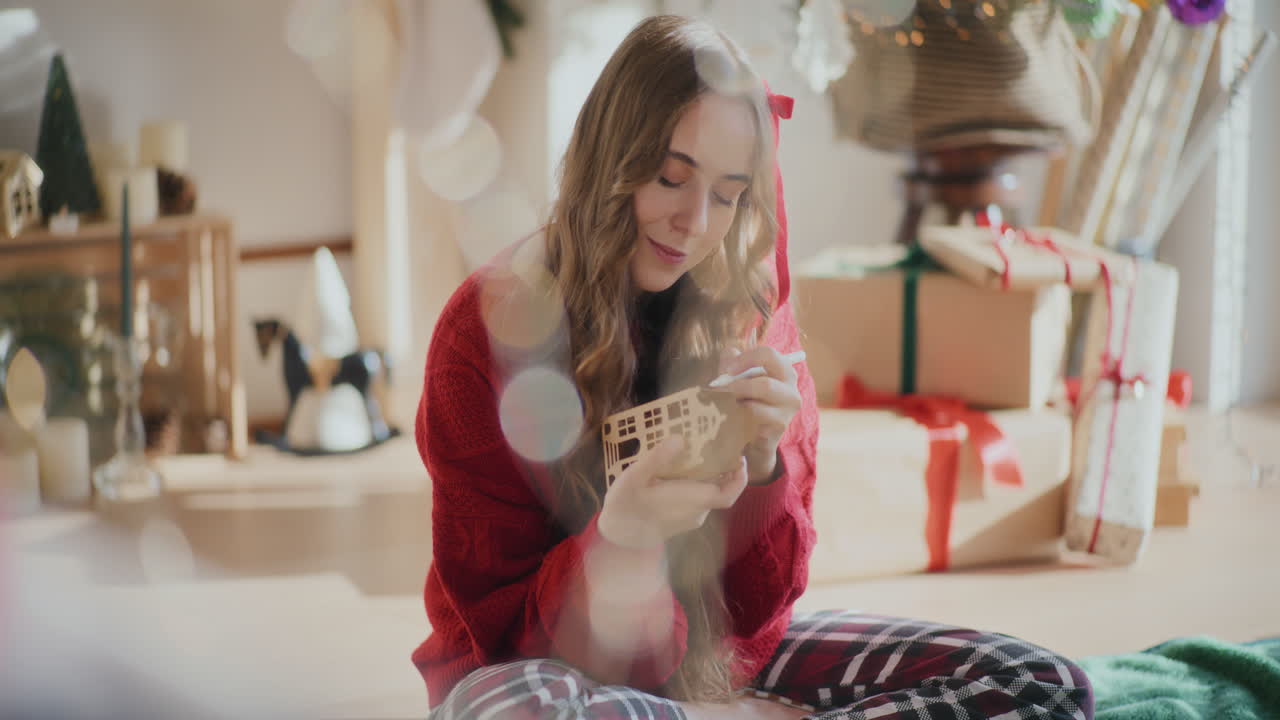 mujer coloreando el ornamento de la casa de cartón durante la navidad en casa