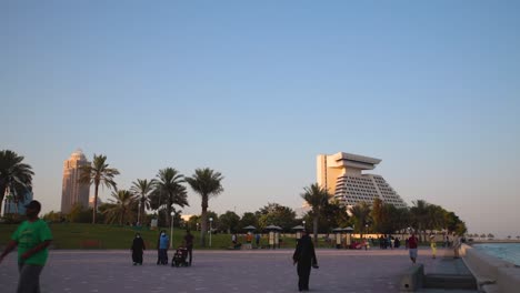 doha cor-niche promenade at sunset showing people sitting , walking and sheraton hotel in the background