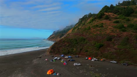 Sunny clear blue skies misty rugged rocky mountainside cliffs bluffs untouched remote USAL Beach campground California aerial drone camping Sinkyone Wilderness Lost Coast Trail upwards motion