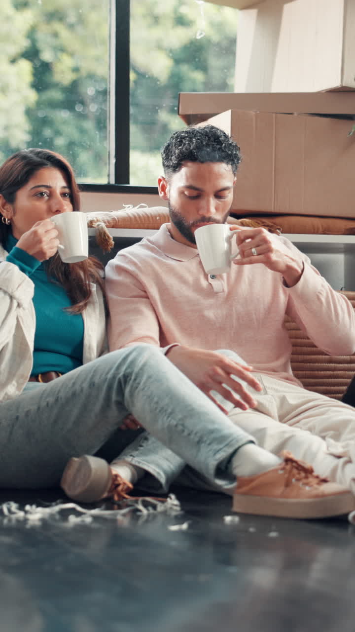 Par, der drikker kaffe og snakker på gulvet i deres nye hjem