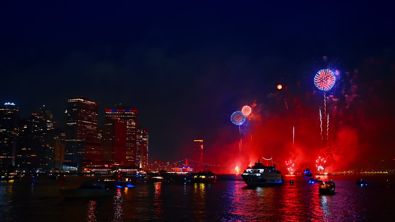 Dark waterscape of the East River illuminated by the flashes of striking fireworks. Stunning celebration show in New York, USA