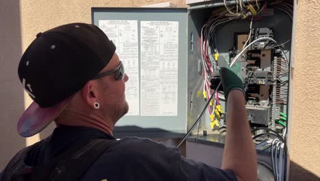 electricista instalando líneas en una caja de circuitos en una casa residencial para conectar nuevos paneles solares