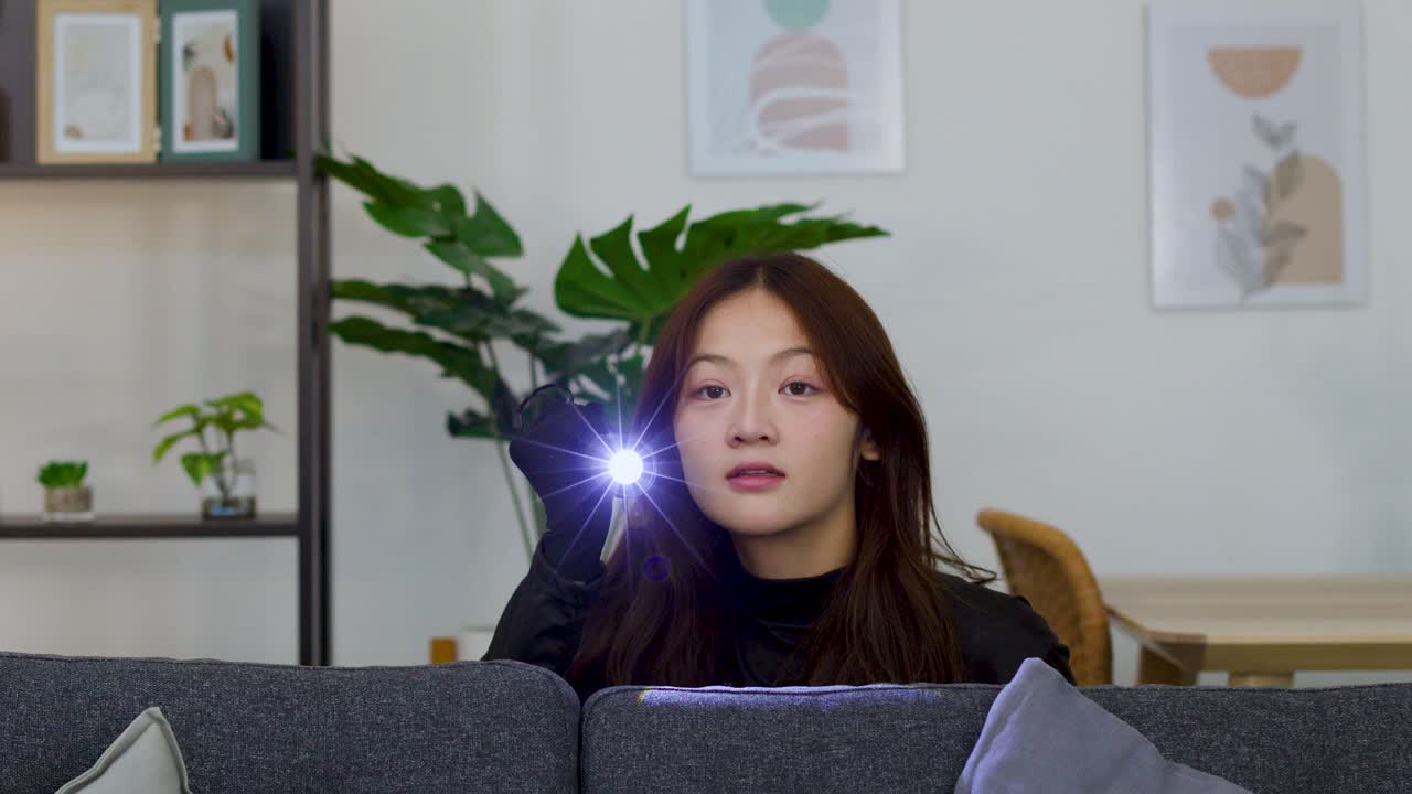 一名身穿黑衣的亞洲女子，用電筒搜尋昏暗客廳