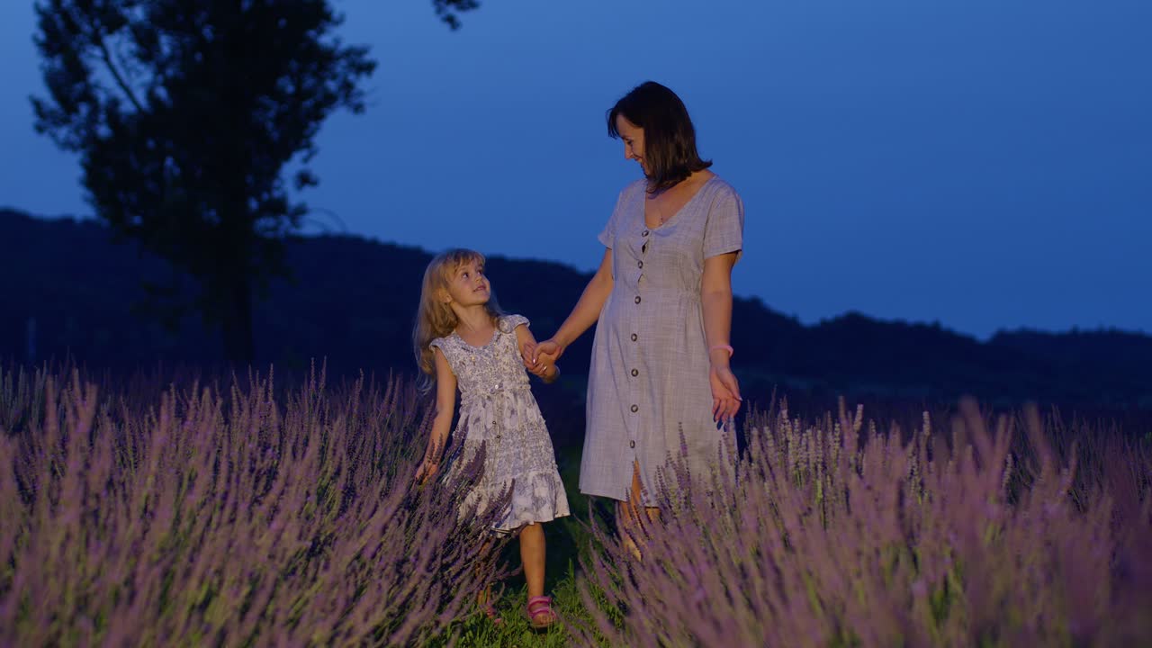 Adorable little cute daughter child kid walking with mother in lavender field, playing with flowers