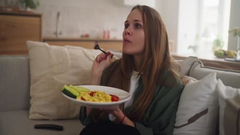 mujer tomando el desayuno en el sofá