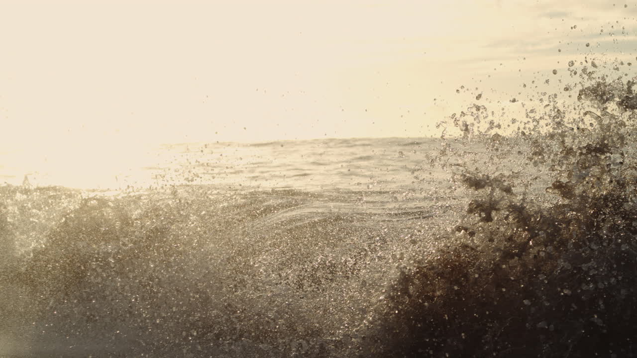 Backlit wave folds in slow motion at sunrise, glowing crest and sparkling foam highlight light