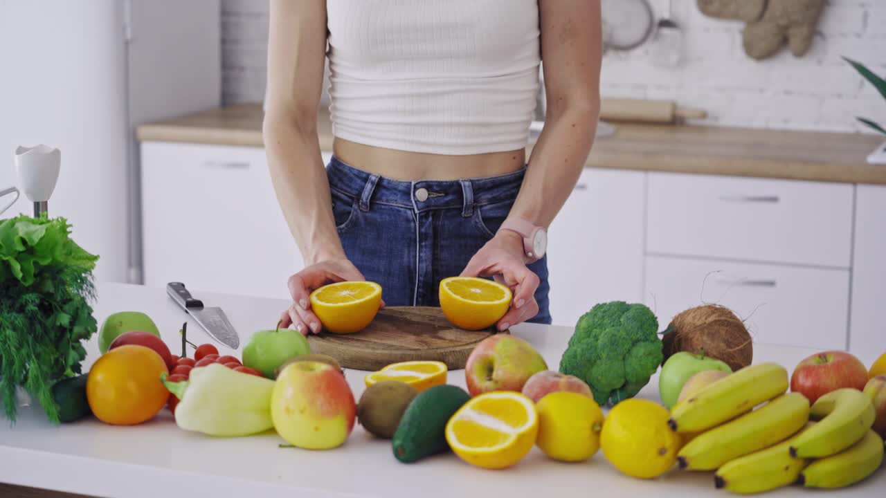 Woman cutting fruit in the kitchen. Beautiful young woman preparing fruit salad in kitchen