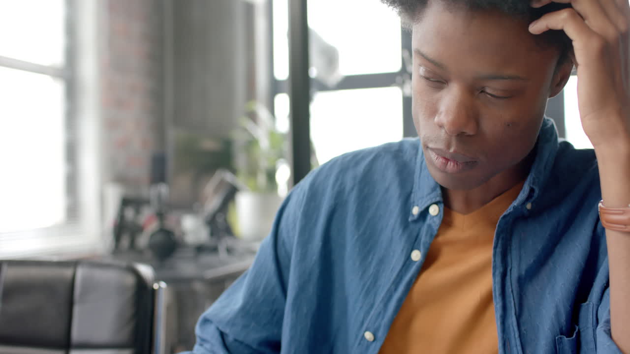 Thoughtful african american casual businessman sitting at desk using laptop at home, slow motion