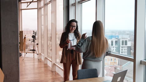 business people communicating about work. ladies discuss working issues standing at the window in office.