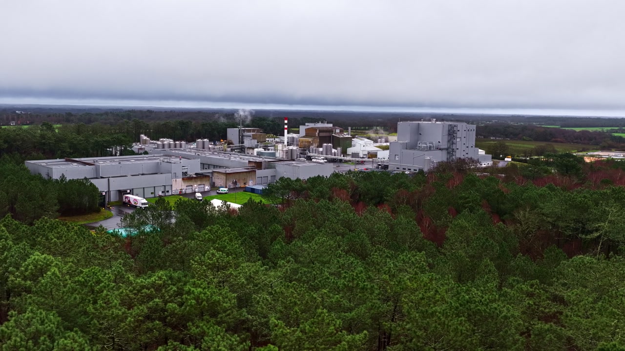 High angle view of a huge factory with warehouses surrounded by vast forests.
