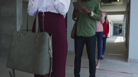 People wearing face masks using smartphones while standing in queue