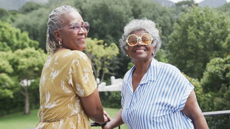 Retrato-De-Amigas-Afroamericanas-Mayores-Con-Gafas-De-Sol-Riéndose-En-El-Balcón,-Cámara-Lenta