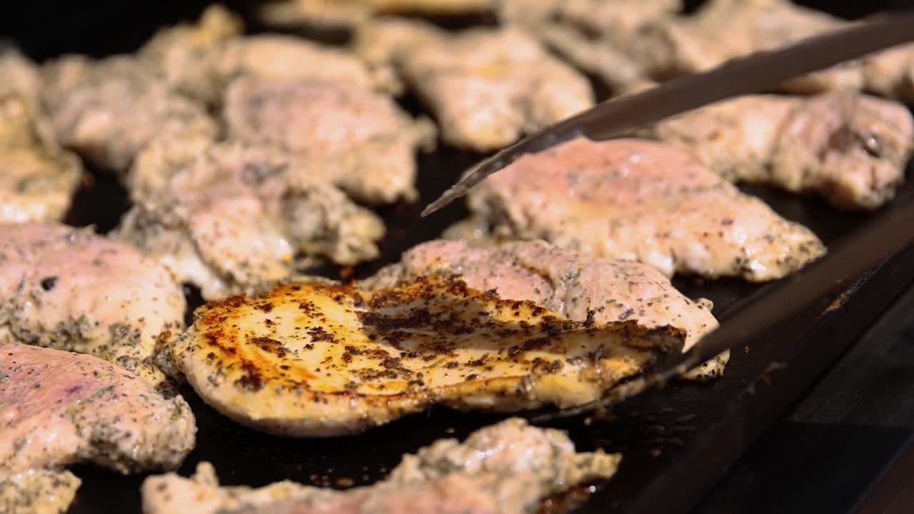 Turning The Meat Fillet With Spices On The Griddle Using Tongs. - closeup shot