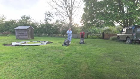 mother daughter teamwork cutting garden grass area with petrol mowers