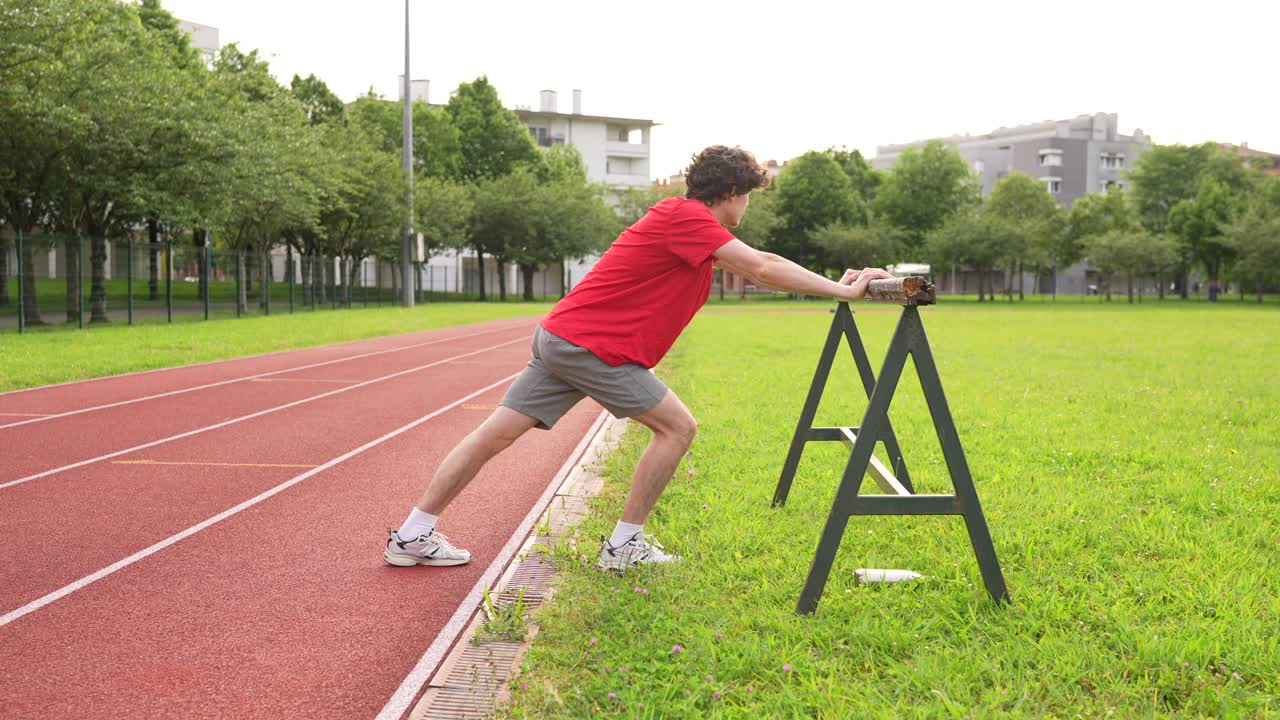 Man stretching on a hurdle at an athletic field