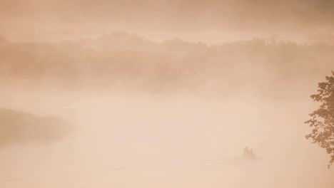 tranquilo lago, río y hombre pescando desde un viejo barco de pesca de remos de madera en el hermoso amanecer brumoso en la mañana de verano. pescador está en el barco. naturaleza rusa