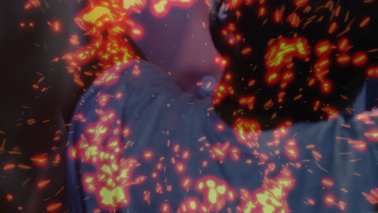 Center woman standing, right man turning, raising arm as ember sparks rising over backs to music