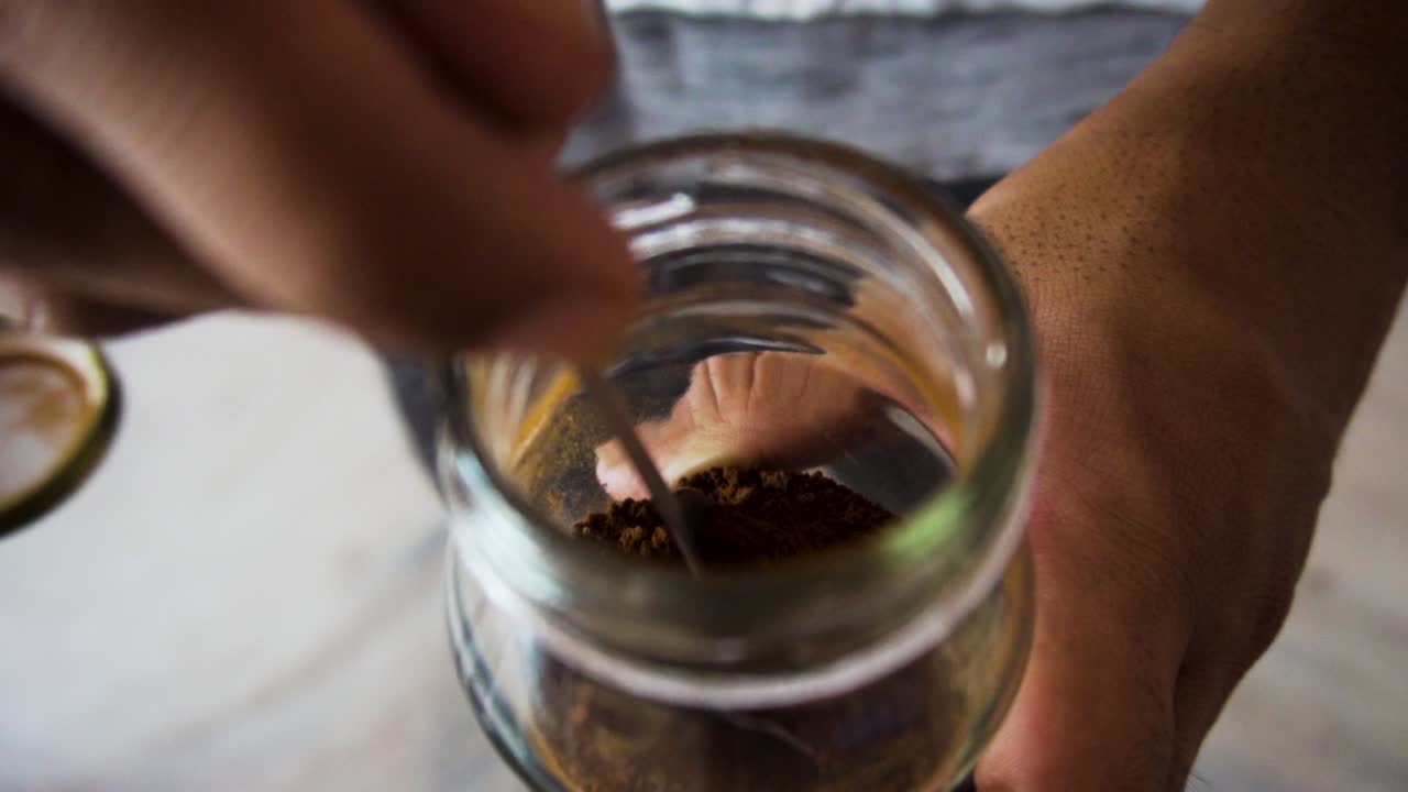 커피 가루를 추가하기 위해 숟가락을 사용하는 남자