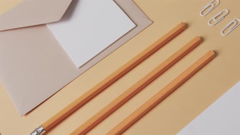 una capa plana de lápices, un sobre y una nota con espacio para copiar sobre un fondo amarillo