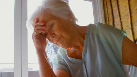 front view of old caucasian senior woman sitting on sofa in a comfortable home 4k