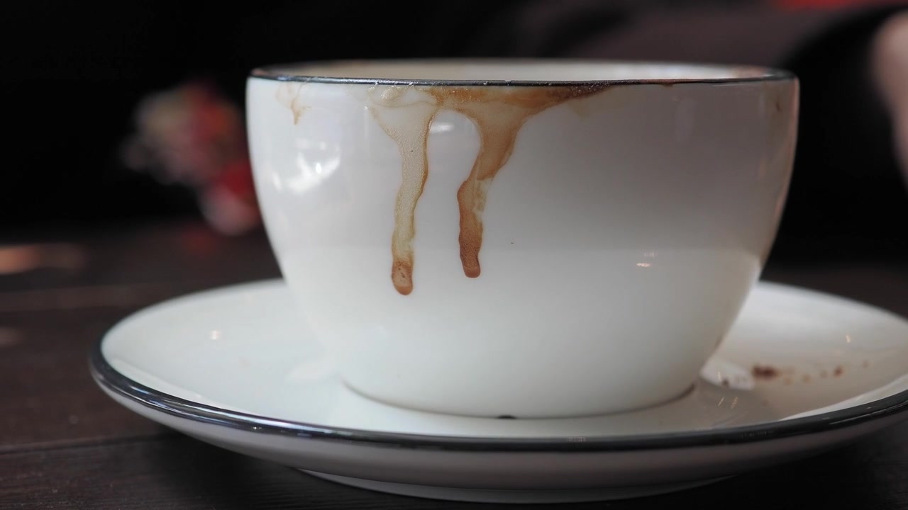 Tazza di caffè bianca usata con macchie di caffè gocciolanti