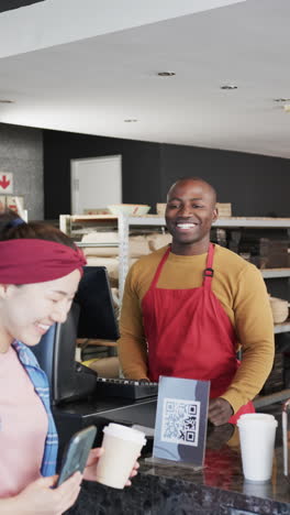 vertical video of happy diverse worker and customer with coffee waving hands in slow motion