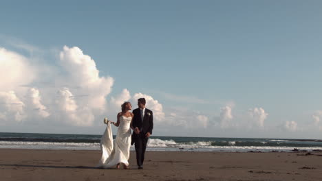 happy newlywed couple walking on the beach