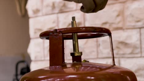 man doing liquefied petroleum gas cylinder refilling and gas leakage through valve close up at day