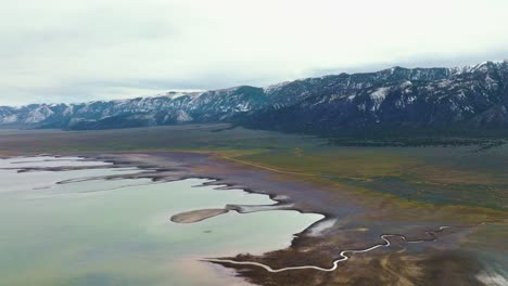 AERIAL---Beautiful-snowcapped-mountains-next-to-Scipio-Lake,-Utah,-wide-shot-reverse