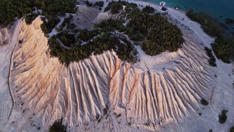 rummu quarry in estonia filmed by drone reveals the massive white ash hill next to a flooded quarry with clear blue waters and old ruins surrounded by lush green trees