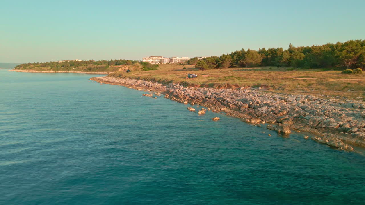 orilla rocosa con turistas estacionados en el mar croata durante la puesta de sol