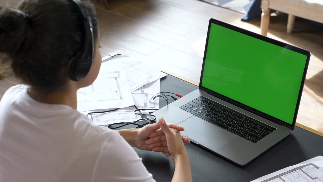una joven india lleva a cabo una conferencia en línea, se entrena con personas, utiliza una computadora portátil con una pantalla verde. habitación brillante en casa