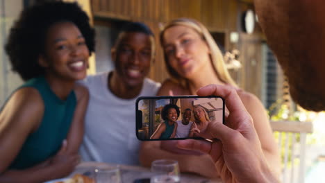 group of smiling multi-cultural friends outdoors at home posing for picture on mobile phone together