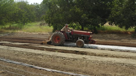 granjero conduciendo un tractor vintage en cámara lenta, vista de perfil de máquina agrícola haciendo surcos