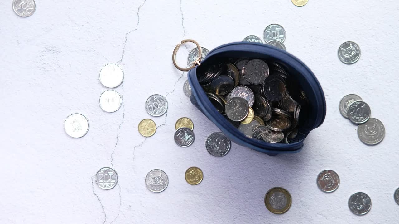 monedas en una bolsa azul en una superficie gris claro